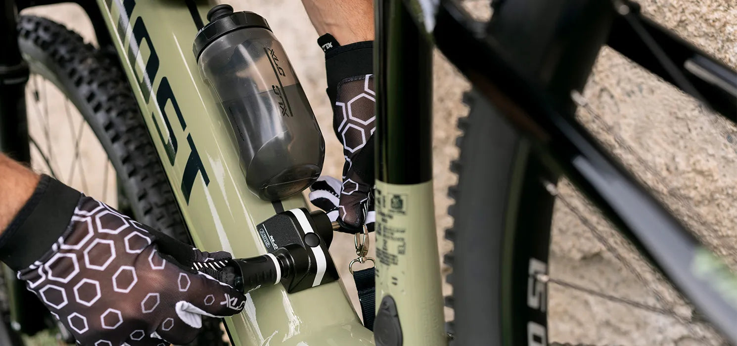 Hands in cycling gloves securing a lock on a GHOST ebike frame.